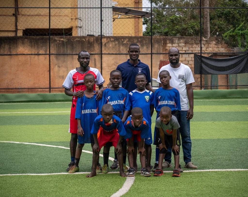 Kisasa Zone squad posing with coaches on the pitch
